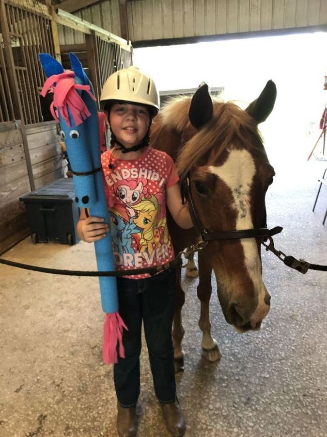 A child with horse and toys playing at horse camp